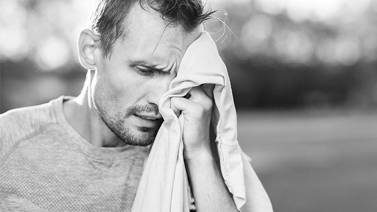 A Black And White Image Of A Male Athlete Wiping His Brow With A Towel After An Activity