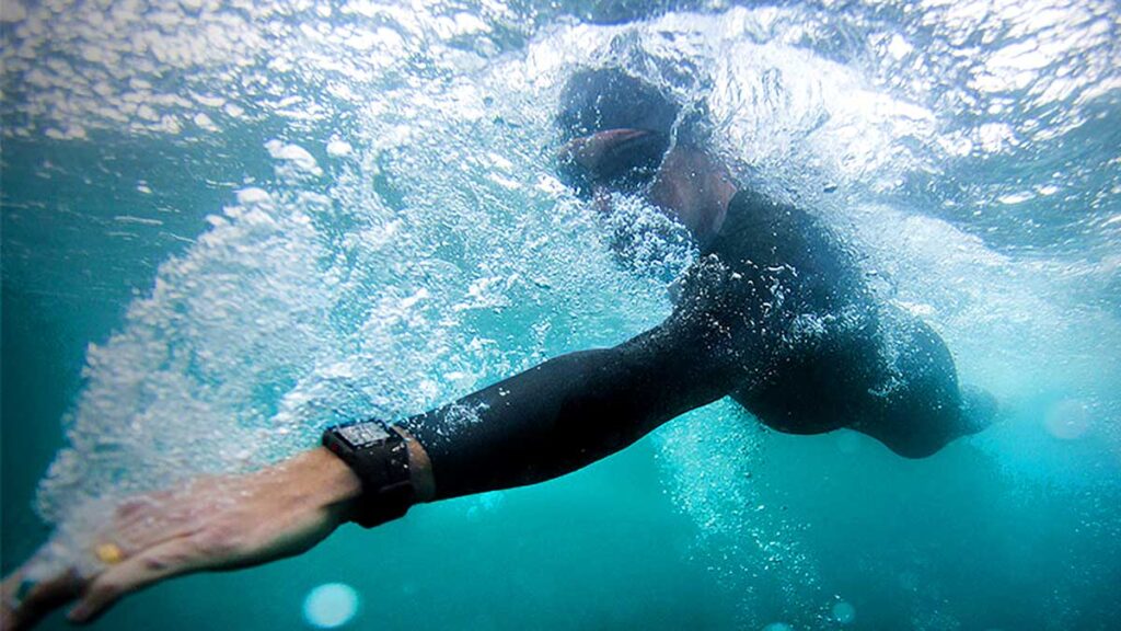 a swimmer under the surface during a freestyle stroke as bubbles surround him