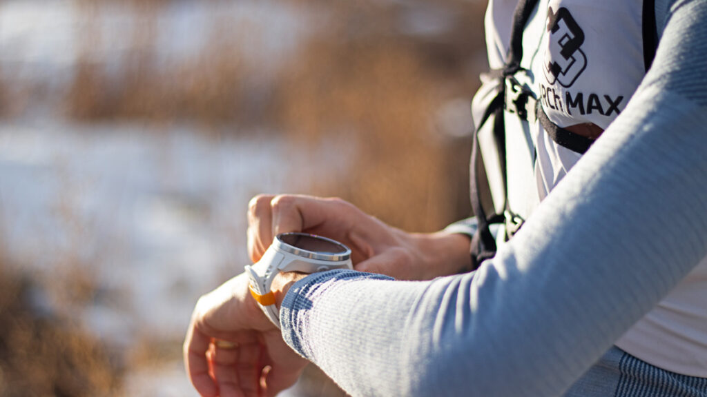 a female athlete looking at her smartwatch in a snowy setting