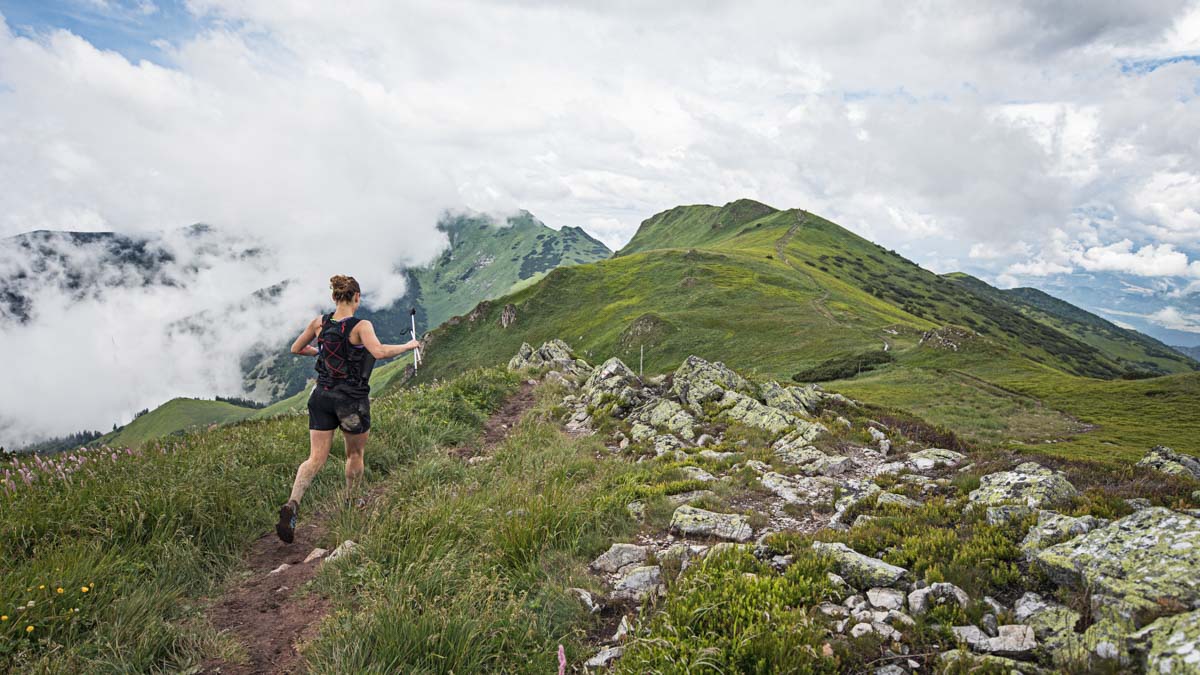 Female Runner Running Fast On Technical Ridge Trail In The Green