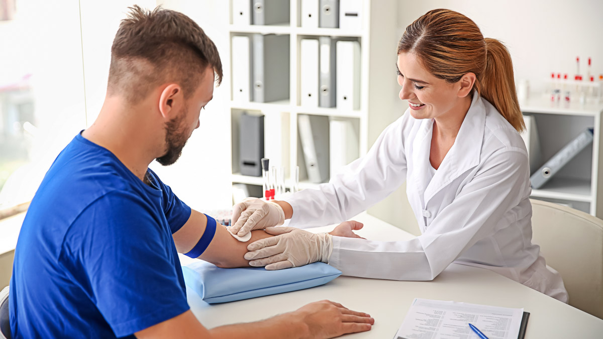 Female Doctor Preparing Patient For Blood Draw In Clinic