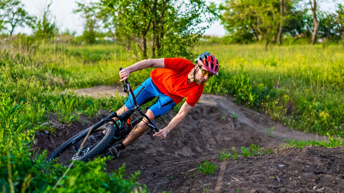 A Professional Cyclist In A Bright Orange T Shirt Rides Under A Switchback