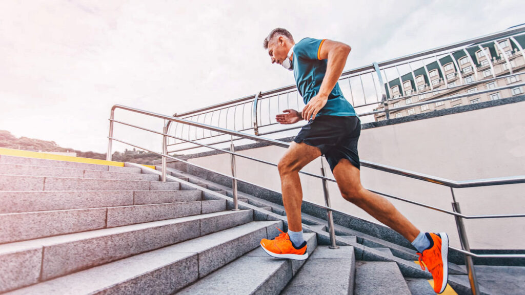 a masters male runner going up a set of bleachers in a stadium 