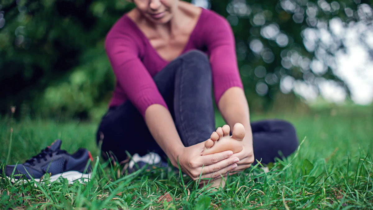 Foot Pain .woman Sitting On Grass.