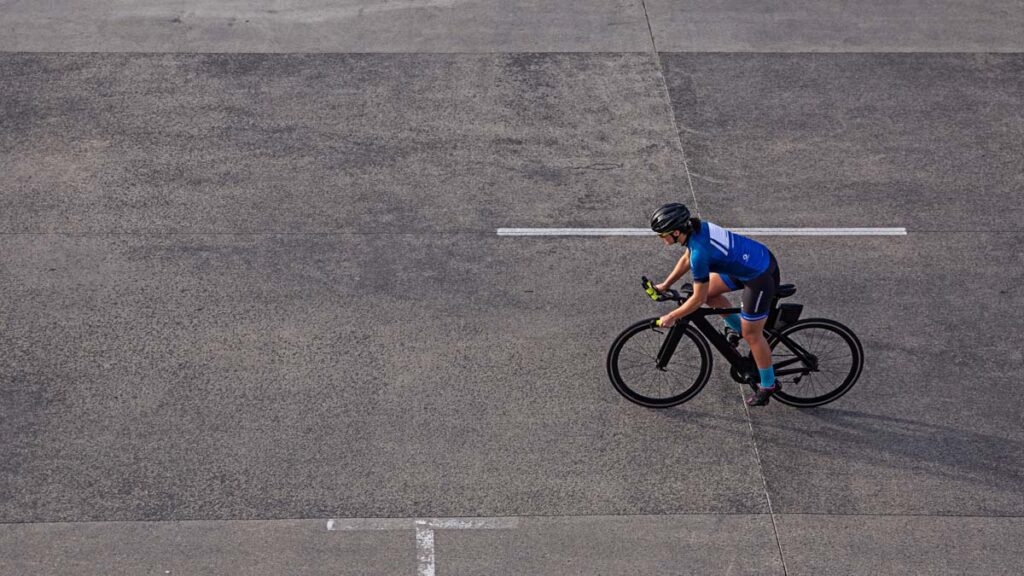 a cyclist on an empty road photographed from above 