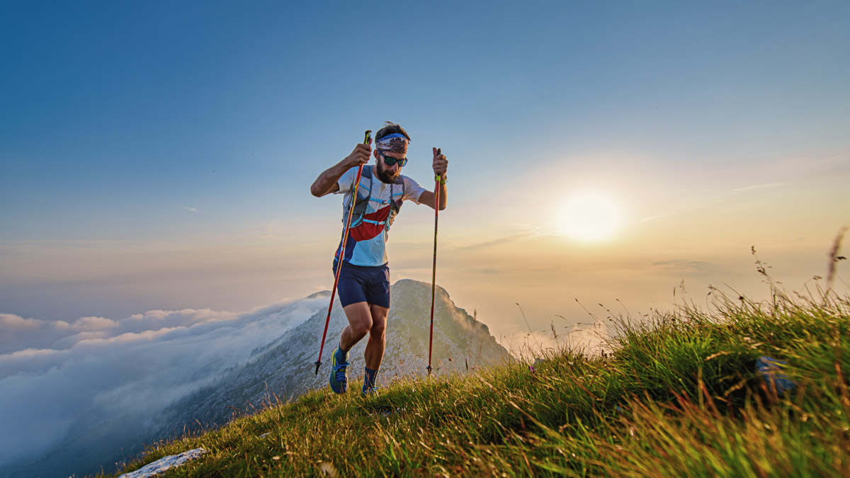 Man With Poles In The Mountains With Sunset Behind