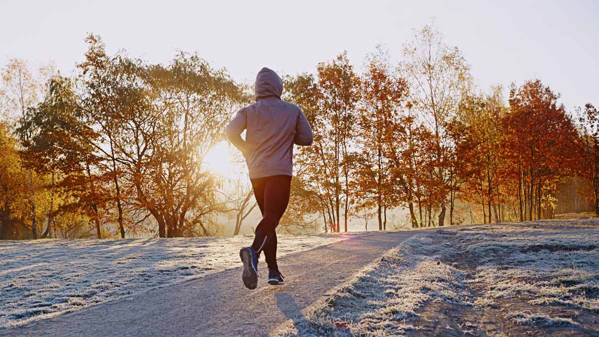 Young Man Running At Park During Frosty Autumn Morning