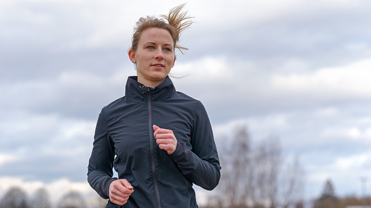 Fit Young Woman Working Out Jogging Along A Dirt Road In The Countryside On An Overcast Winter Day Approaching The Camera In A Close Up View