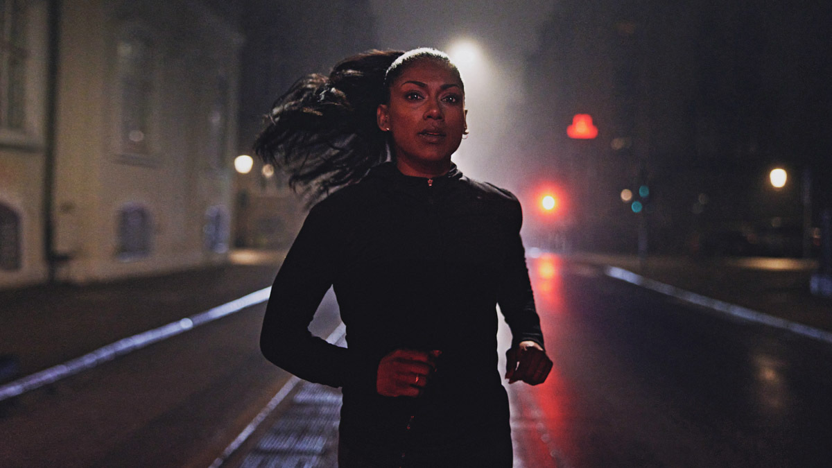 An Image Of An Attractive Fit Woman Running In The Dark On A City Street At Night With City Lights