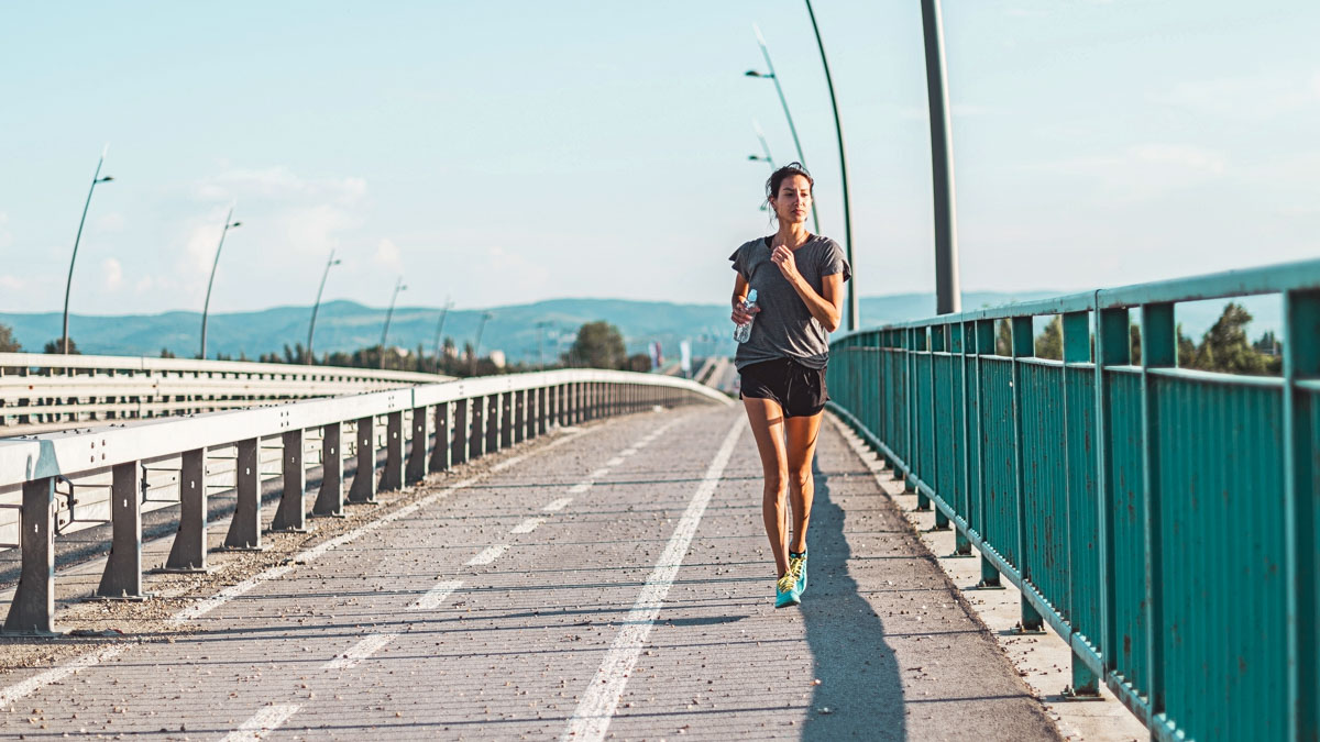 Image Of A Young Woman Jogging On A Bridge In Zone 2 For Aerobic Base Training So That She Can Build An Aerobic Base