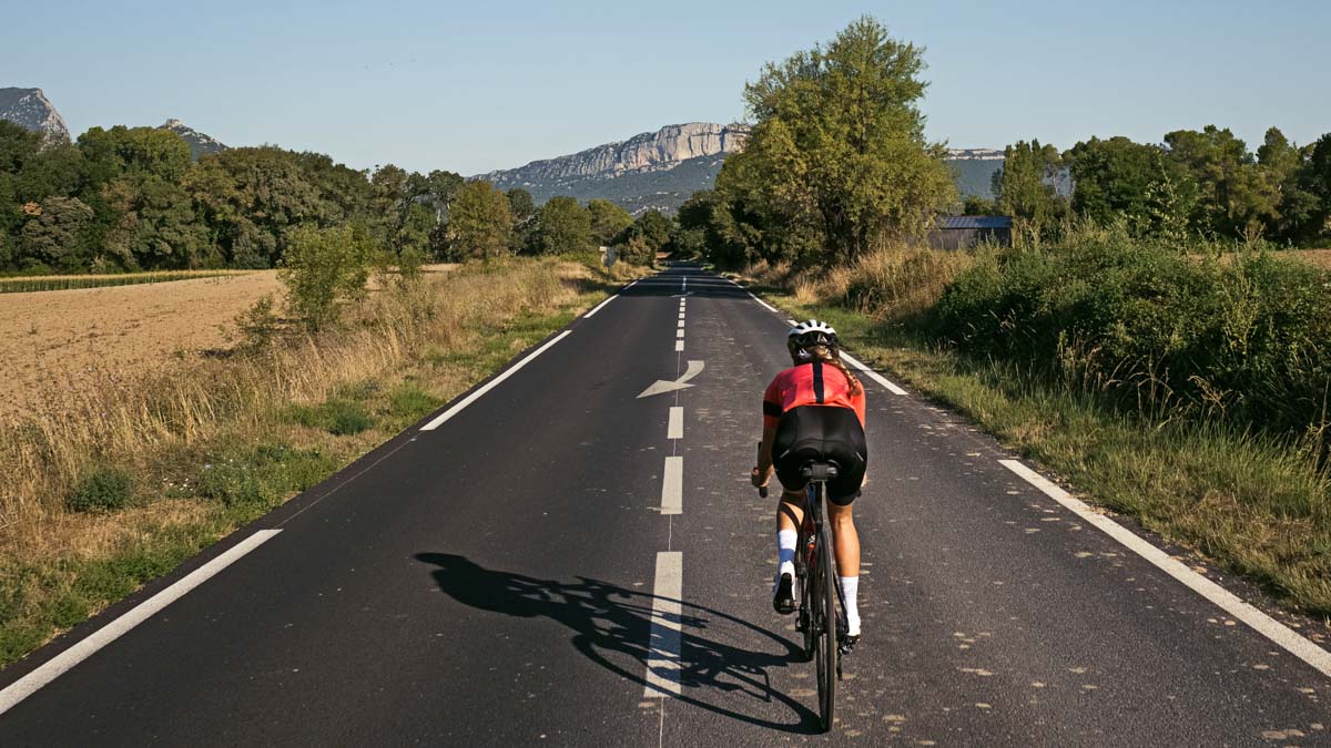 Female Cyclist Doing High Intensity Interval Riding Through Narrow Country Road In France With Mountains