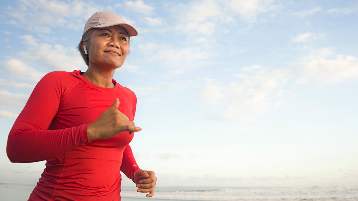 Image Of An Older Asian Woman Who's Taken Hormone Replacement Therapy Running On The Beach