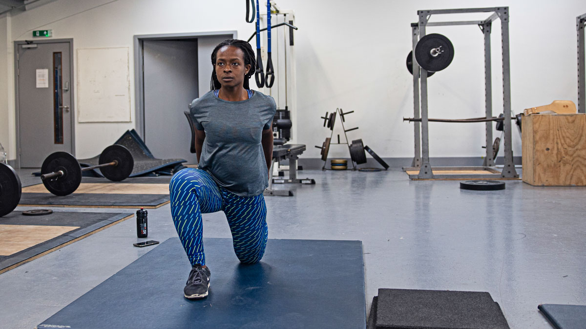 A Woman Working Out In A Gym With Weights In The Background