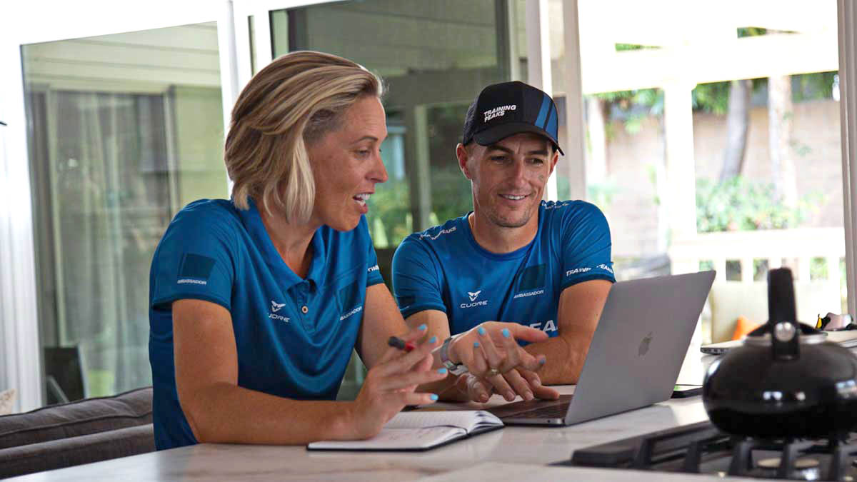 Two Coaches Review Training Peaks Data On A Computer From Their Home Office