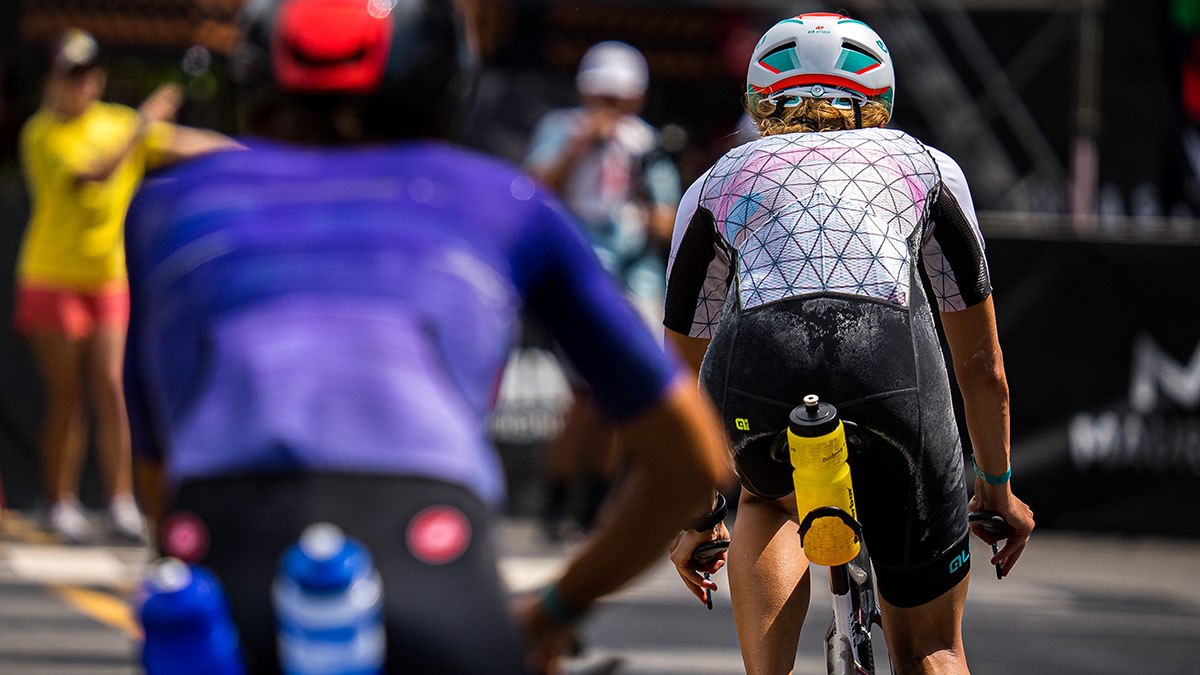 Woman With Sweat Stains On Their Triathlon Suits Ride Their Bikes Into Transition 2 During A Race In Kona