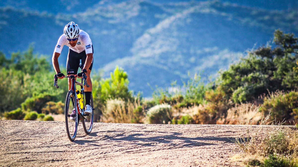 A Male Rider Pedaling Up A Steep Dirt Road In The Mountains On A Training Ride