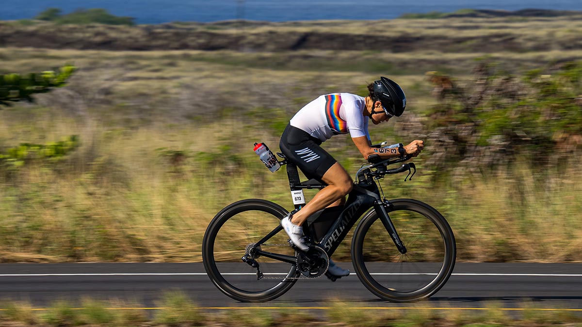 A Triathlete Riding Their Bike On Course At An Ironman As The Sun Shines Down