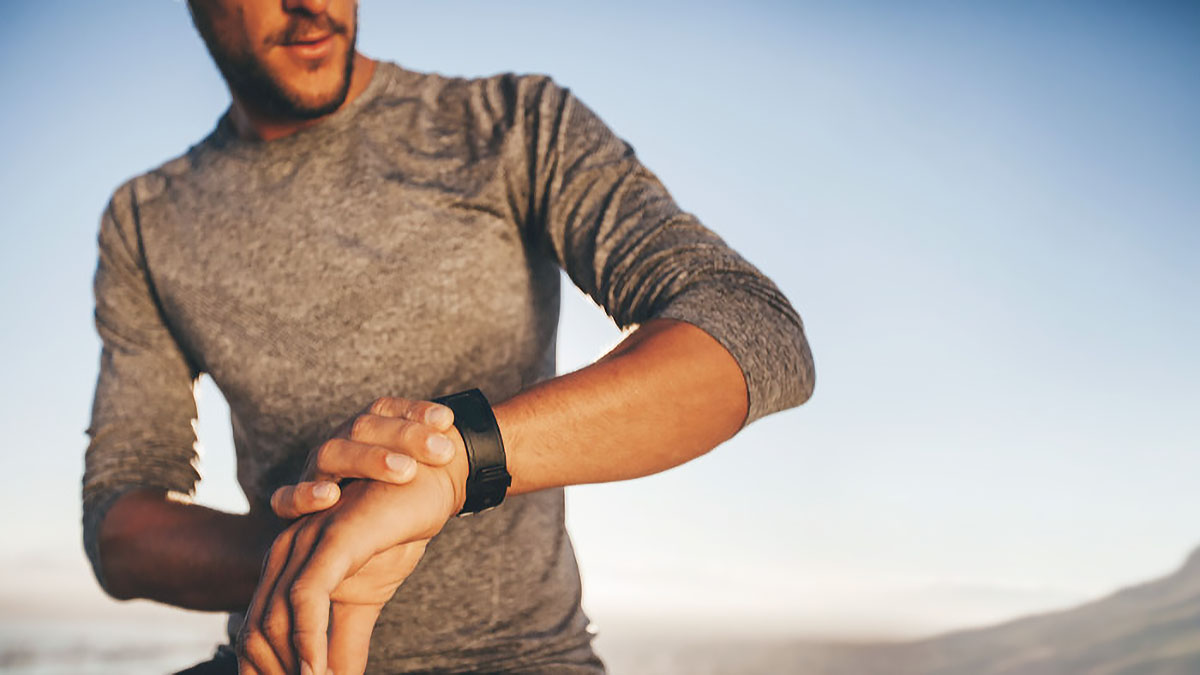 A Male Runner Looking At His Watch In The Early Morning