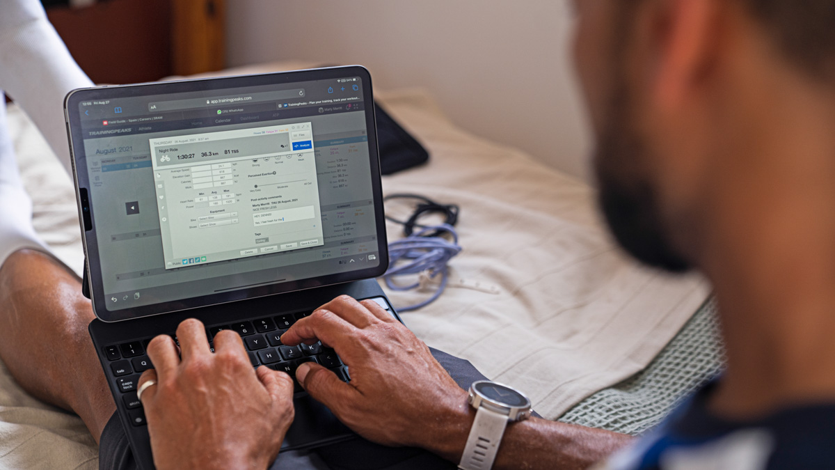 A Man Sitting At A Computer Working On Trainingpeaks' App