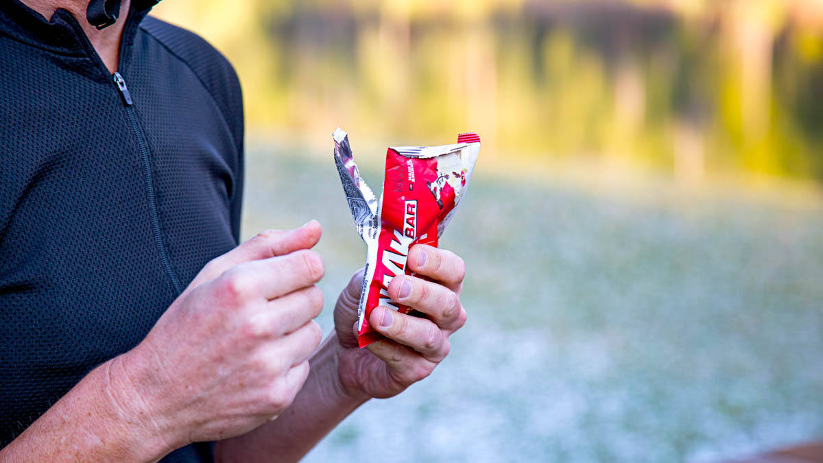 Trainingpeaks Cyclist Eats Snaak Bar With Red Wrapper On Bike Trail