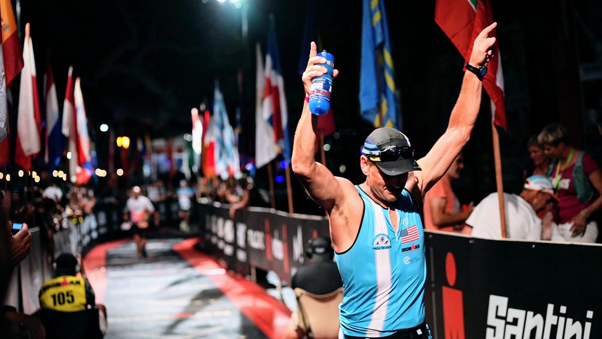 A Triathlete Coming Into The Finish Of An Ironman Race With His Hands Up Above His Head In Celebration