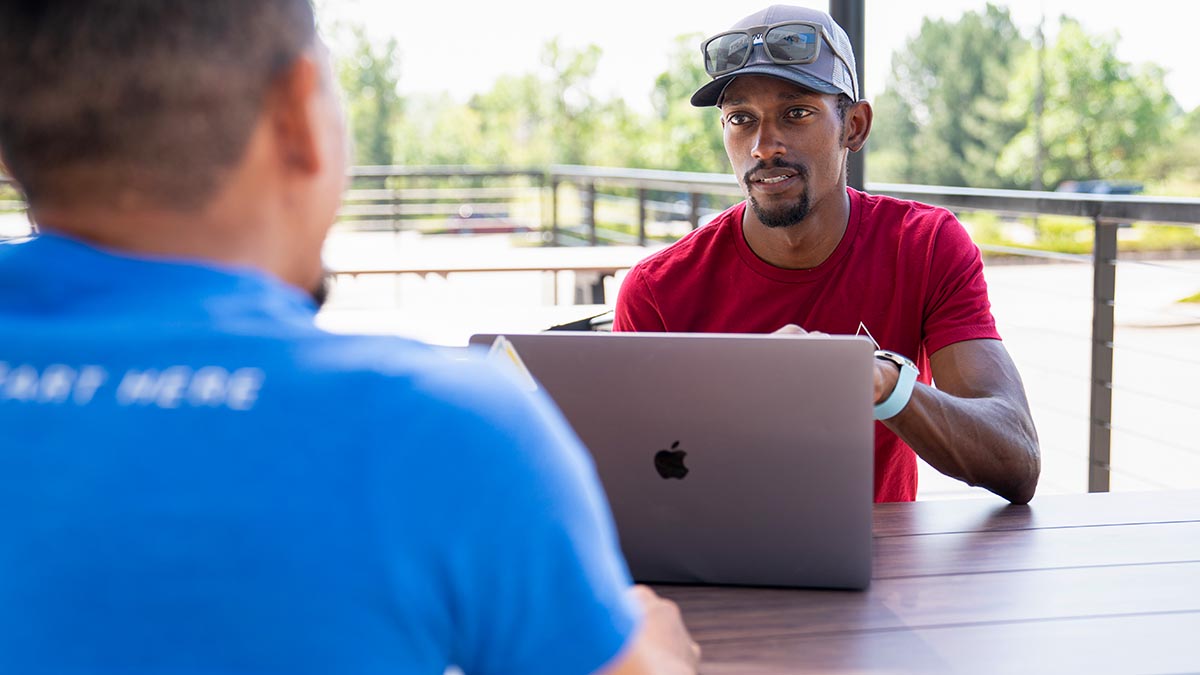 A Black Cycling Coach Talks With An Athlete After A Training Event