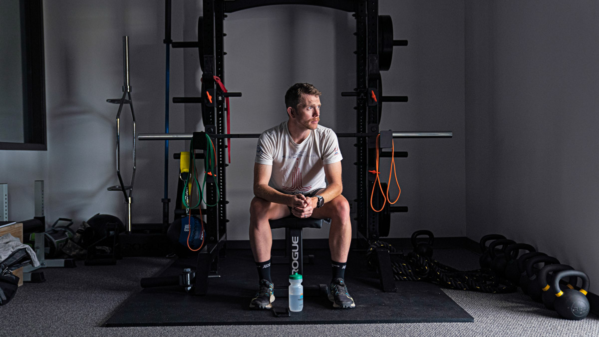 A Man Sits On A Weight Bench In A Fitness Facility As Equipment Sits Around Him.