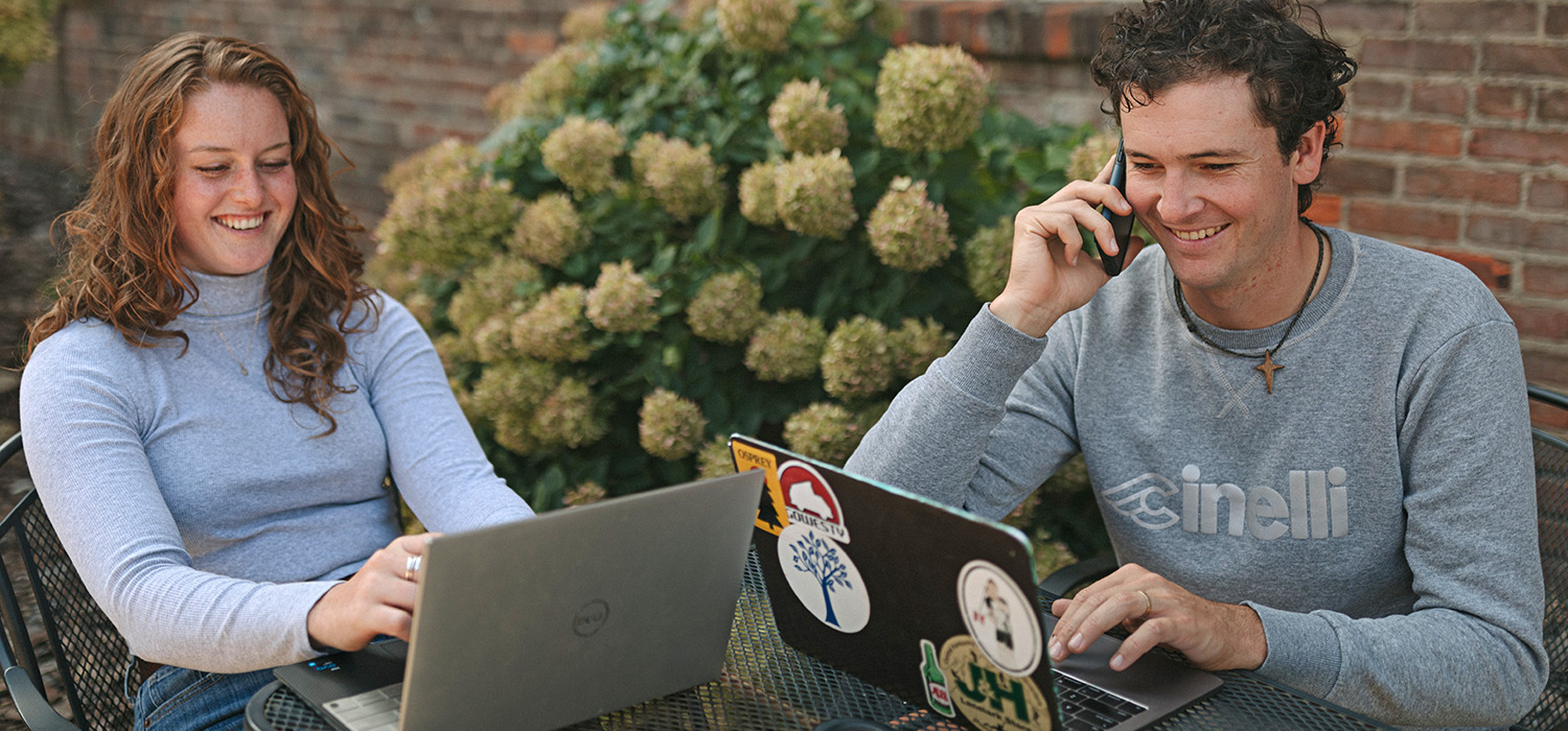 Coach Ruben Bacon and a colleague work on laptops outside of a coffee shop