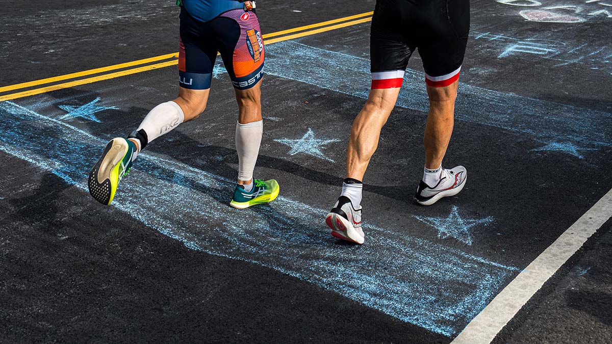 The Legs Of Two Men Running On A Street With Chalk Drawings On It.