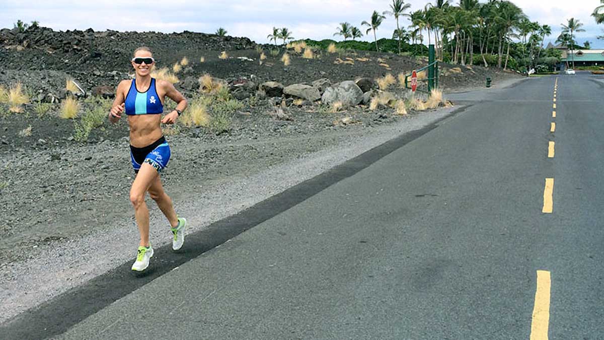 A Female Triathlete Running On The Road Smiling At The Camera