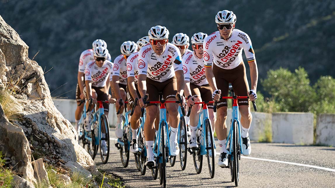 Team Of Cyclists Riding Up A Mountain Road